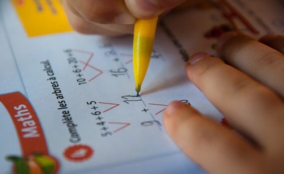Photographie rapprochée d'une main tenant un crayon pousse-mine. La personne complète un arbre à calcul dans un cahier d'activités de mathématiques.