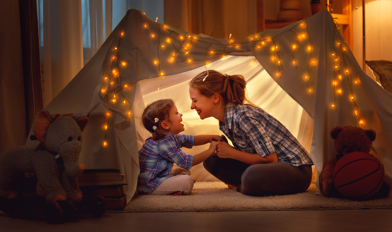 Photographie d'une mère et de sa fille riant dans une cabane intérieure, entourée de toutous.