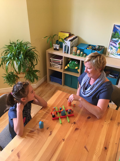 Photographie de Josée Bellehumeur, enseignante consultante en focusing, enseignant à une jeune fille une stratégie à l'aide d'une activité ludique.